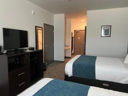 a hotel room with two beds and a flat screen tv at The Grove Inn and Suites in Eagle Grove