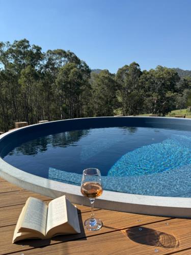 Ein Glas Wein und ein Buch auf einem Tisch in der Nähe eines Swimmingpools in der Unterkunft Cedars Mount View (Adults Only) in Mount View
