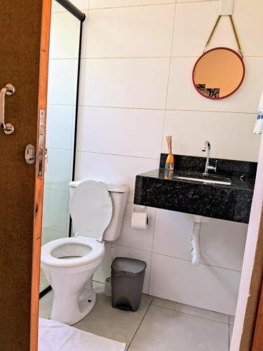 a bathroom with a toilet and a sink at Chalé piscina compartilhada com cozinha in Imbituba
