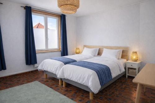 a bedroom with a bed with blue curtains and a window at Appartements Entiers - Centre de Tournai in Tournai