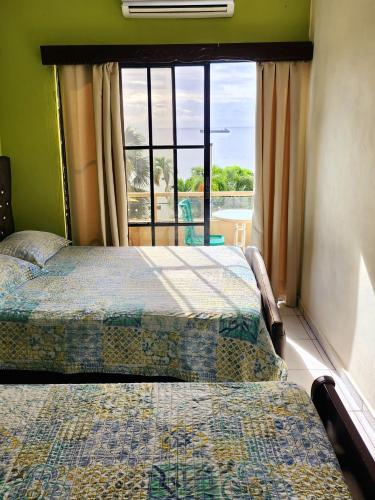 a bedroom with two beds and a window with a view at Hotel La Llave del Mar Zona Colonial in Santo Domingo