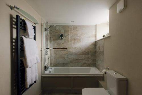 a bathroom with a bath tub and a toilet at Dunsa Cottage Bakewell Peak District in Bakewell