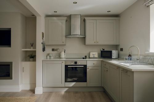 a kitchen with white cabinets and a stove top oven at Stable Cottage Chatsworth Estate in Baslow