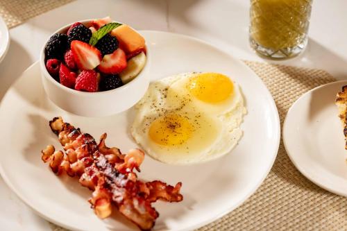 a plate of breakfast food with eggs bacon and fruit at Hotel Dax in Addison