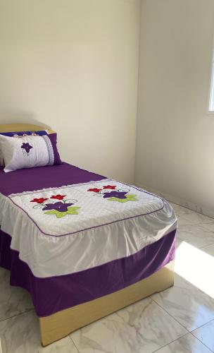 a bed with a purple and white comforter at Apartamento in Espirito Santo Do Pinhal