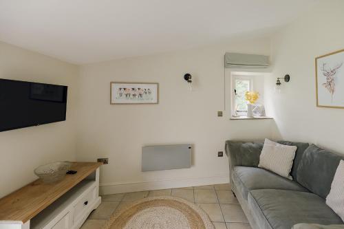 a living room with a couch and a flat screen tv at The Old Wash House Chatsworth Estate in Baslow