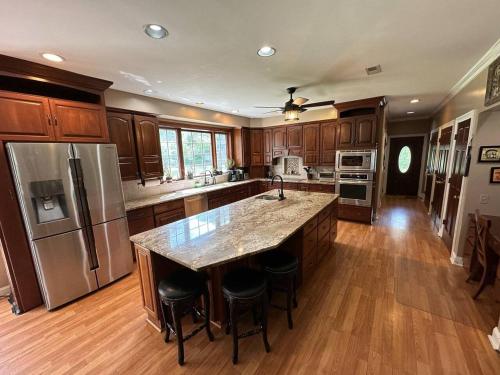 a large kitchen with wooden cabinets and a large island at Large Home with Private Pool, Gym, Sauna, 7 Bedrooms, Sleeps 21 in Severn