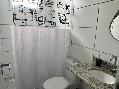 a bathroom with a shower curtain and a toilet and a sink at Vila dos Ventos in São Pedro da Aldeia