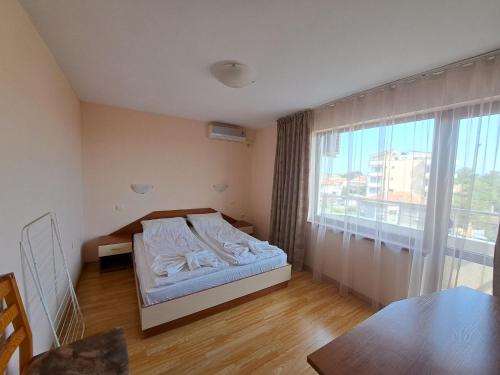 a bedroom with a bed and a large window at Guest House Lazur in Obzor