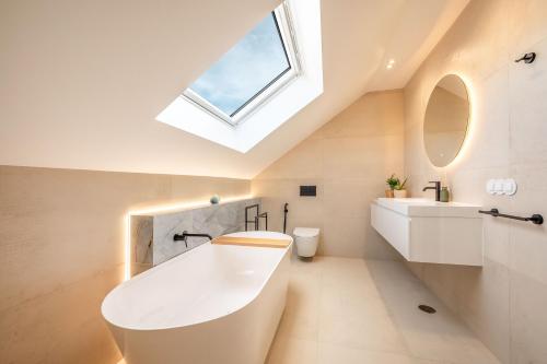 a bathroom with a large white tub and a skylight at Villa Flora in Colares