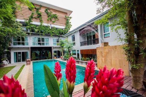 una piscina frente a un edificio con flores rojas en ตำหนักวิลล่า 10 ห้องนอน พร้อมสระว่ายน้ำส่วนตัว en Pattaya South