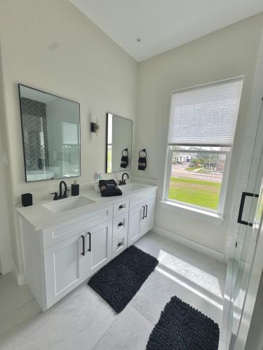 a white bathroom with two sinks and a window at The Grand Harris in Houston