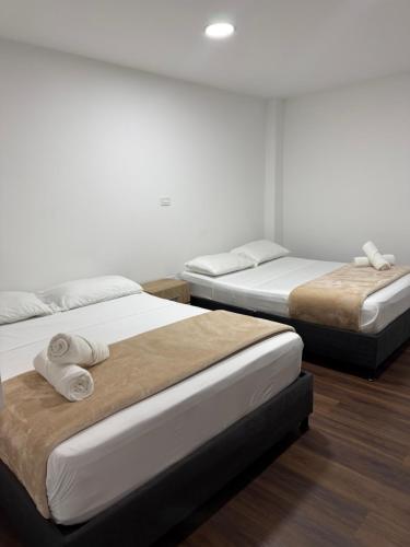three beds in a room with white walls and wood floors at Travesía Quindiana in Filandia