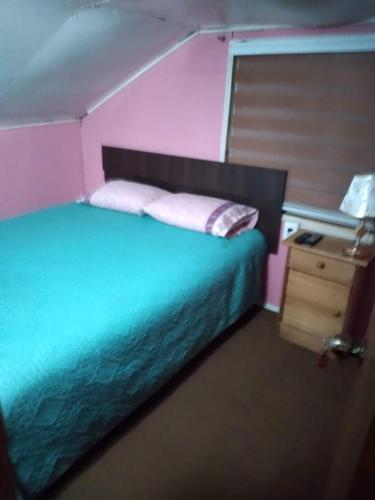 a pink bedroom with a bed and a night stand at Hospedaje Domiluis in Coihaique
