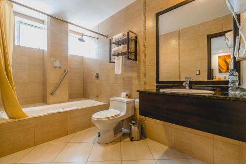 a bathroom with a toilet and a sink and a tub at Zamorano Real Hotel in Loja