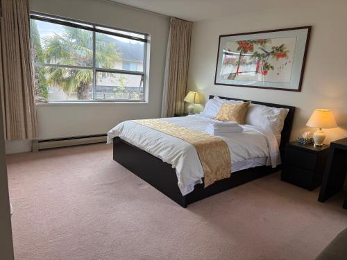 a bedroom with a large bed and a window at As You Wish Suites & Rooms Near YVR with Parking in Richmond