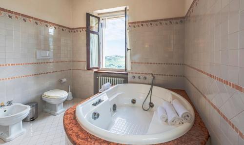 a white bathroom with a tub and a toilet at Villa Bricco Paglieri in Alba
