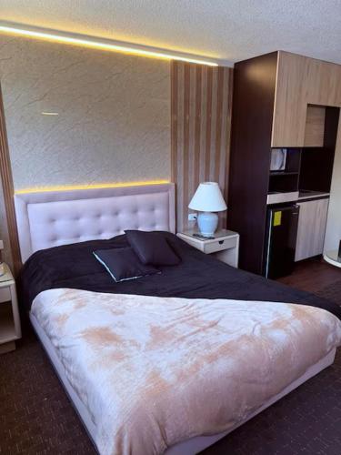 a bedroom with a large bed with a black blanket at Suites Edificio Akros in Quito