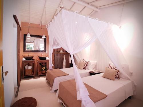 a bedroom with two beds and a mosquito net at Biribandos Rooms - a 300 metros do Quadrado e 900 metros das praias in Trancoso