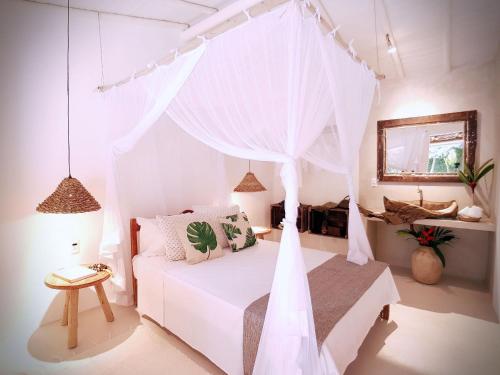 a bedroom with a white bed with a canopy at Biribandos Rooms - a 300 metros do Quadrado e 900 metros das praias in Trancoso