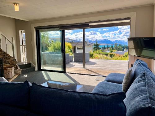 a living room with a blue couch and a large window at Blue Lake Lodge - Lake Tekapo in Lake Tekapo