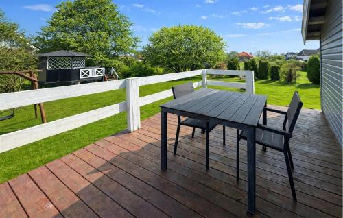 a wooden table and chairs on a deck with a fence at Nice Home In Broager With Wifi in Broager