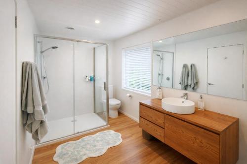 a white bathroom with a sink and a shower at Raglan West Cottage, Surf Side Escape in Raglan