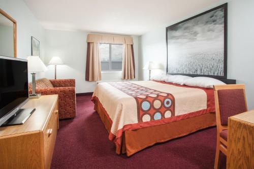 a hotel room with a bed and a flat screen tv at Super 8 by Wyndham Kindersley in Kindersley