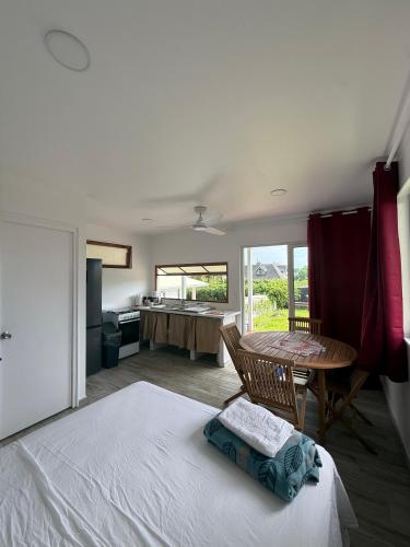 a bedroom with a bed and a table and a kitchen at Tuava - Mirimiri Lodge in Ataiti
