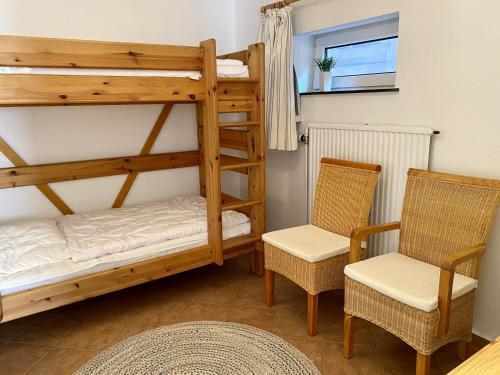 a bunk bed and two chairs in a room at Lerchenweg Bungalow in Westerland