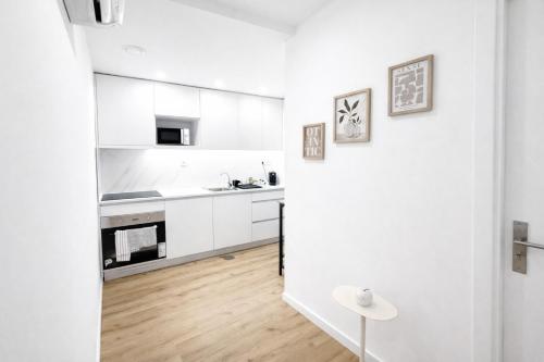 a white kitchen with white cabinets and a wooden floor at CC Room Gaia in Vila Nova de Gaia