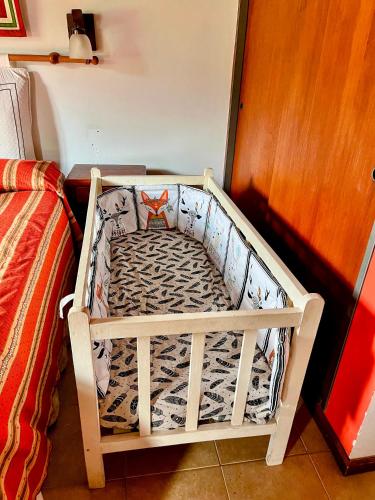 a crib sitting next to a bed in a room at Cabañas Aldea Blanca in Merlo