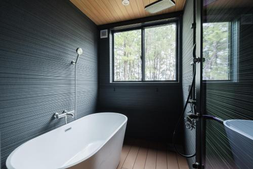 a bathroom with a tub and a window at The Nine States Hotel KARATSU in Karatsu