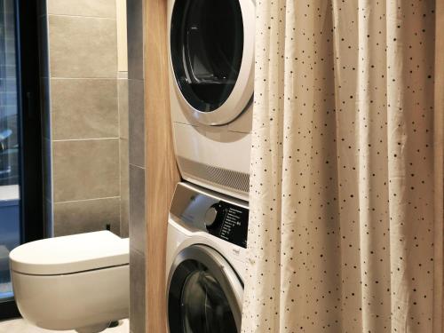 a washing machine in a bathroom next to a toilet at Modern design house with sauna 'Arduenna Silva' in La-Roche-en-Ardenne