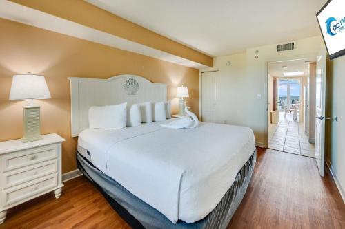 a bedroom with a large white bed and a hallway at Direct Oceanfront Unit Amazing Views with Pools in Myrtle Beach