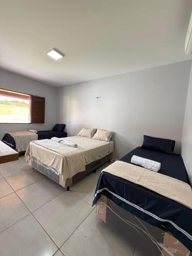 a bedroom with two beds and a couch and a window at Chalés Brisas dos lençóis in Barreirinhas