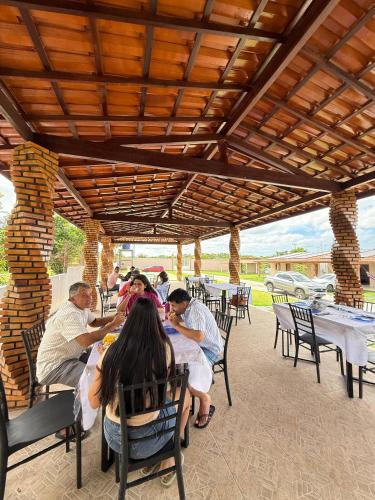 a group of people sitting at tables under a pavilion at Chalés Brisas dos lençóis in Barreirinhas