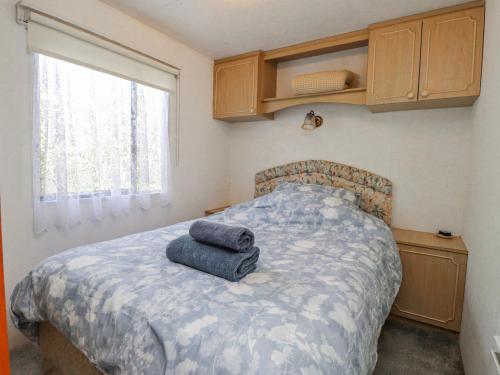 a bedroom with a bed with two towels on it at Fron Dderw Caravan in Holyhead