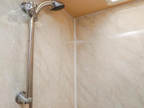 a shower with a shower head in a bathroom at Fron Dderw Caravan in Holyhead