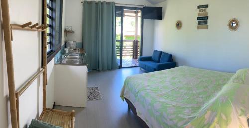 a bedroom with a bed and a blue chair at Rainbow beach Bungalow in Matura