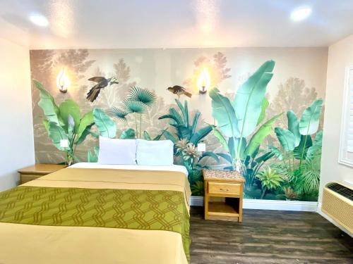 a bedroom with a mural of plants on the wall at Long Beach Motel in Long Beach