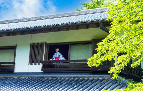 a woman is looking out of a window at Oukai Villa Izumi in Izumi