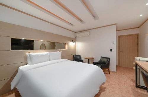 a hotel room with a large white bed and chairs at Daejeon Dunsan ING Hotel in Daejeon