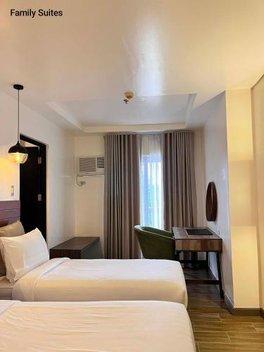 a hotel room with two beds and a desk at RAI ATRIUM SUITES HOTEL - Cauayan in Cauayan City