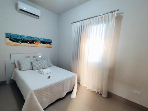 a white bedroom with a bed and a window at Loft 02 - Alvares machado in Álvares Machado