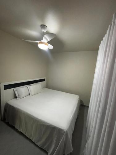 a bedroom with a white bed with a ceiling fan at Casa na Natureza Próx Pomerode e Timbó in Rio dos Cedros