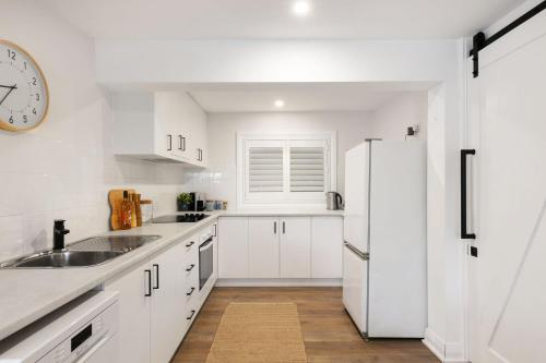a white kitchen with a sink and a refrigerator at Blue View Gerringong in Gerringong