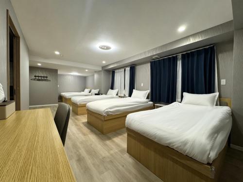 a hotel room with three beds and a table at Ruka Hotel Tennoji in Osaka