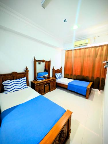 a bedroom with two beds and a desk and a window at Mama Nusantara Hotel in Jertih