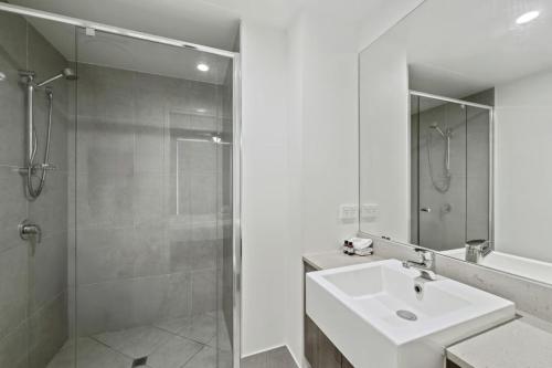 a white bathroom with a sink and a shower at Waterline at Oceanside in Kawana Waters